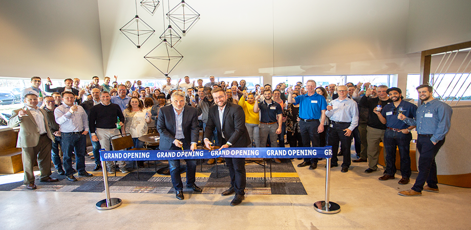Grand opening of a building. Two men cutting a ribbon, with lots of people standing behind them