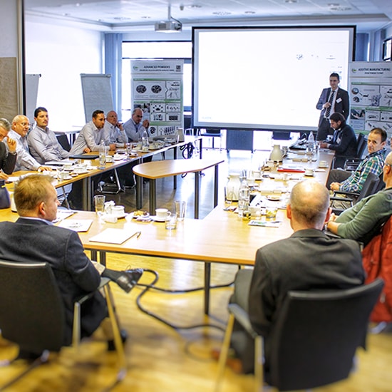 Experts from the automotive industry came together in the GKN Sinter Metals Innovation Center for the first AM Consulting Day. Men sitting around a u shaped table in a conference room