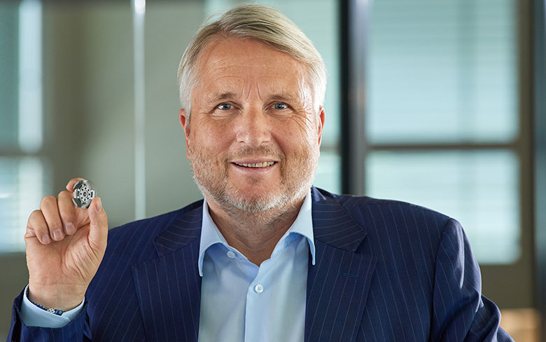 Man in a suit holding a small metal part