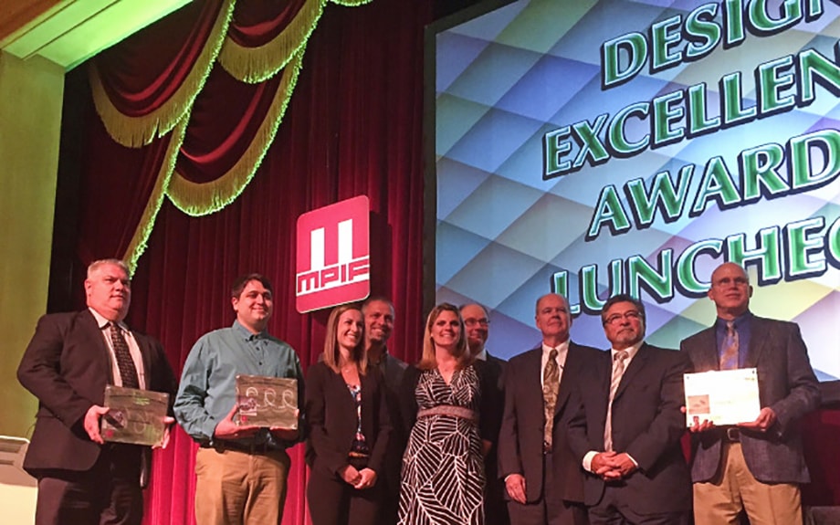 Gkn Sinter Metals Recognized For Design Excellence With Two Mpif Awards. People on a stage accepting the award