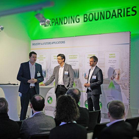 Image of 3 men giving a presentation on a stage